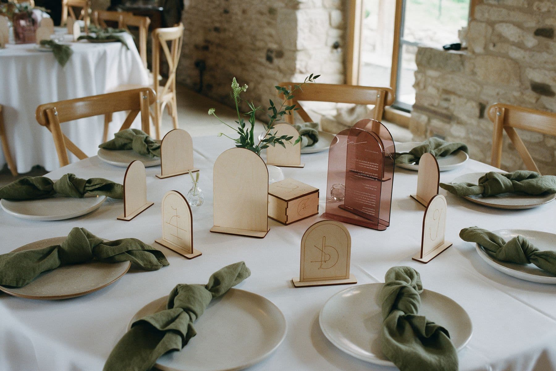 Une table de mariage dressée avec marque-places en bois gravé, menus en acrylique et urne gravée.